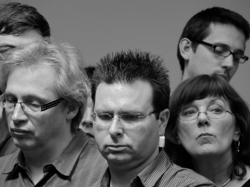 De ontgoocheling druipt van de gezichten tijdens de redactievergadering. Dit zijn de mensen die níét ontslagen zijn. Langzaam dringt het besef door dat zij weleens de grootste slachtoffers van de herstructurering zouden kunnen zijn.