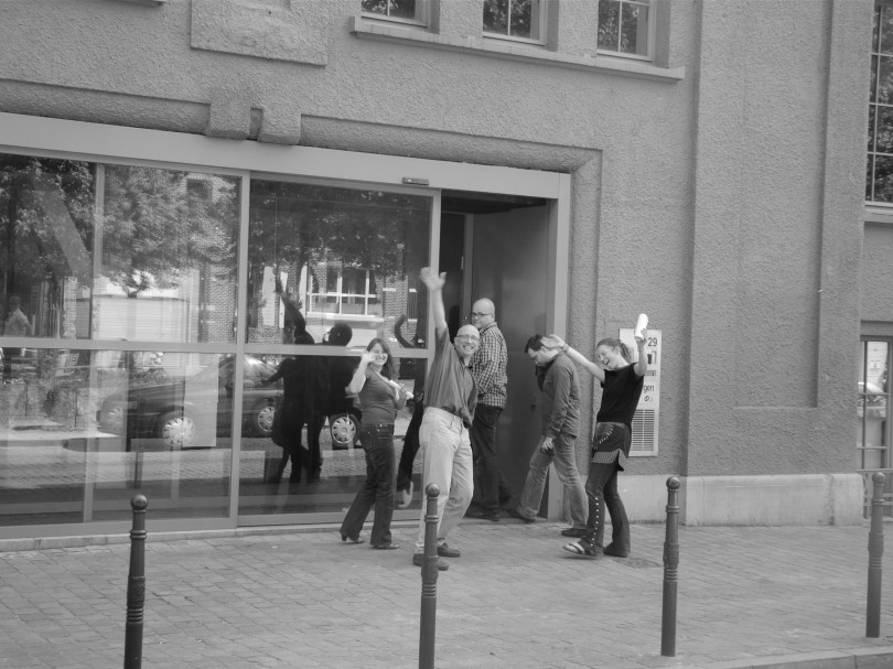 Enkele personeelsleden van De Morgen die het lezersprotest even hebben bijgewoond, keren terug naar binnen voor hoofdredacteur Bart Van Doorne hen een voor een weer achter hun bureau sleurt.