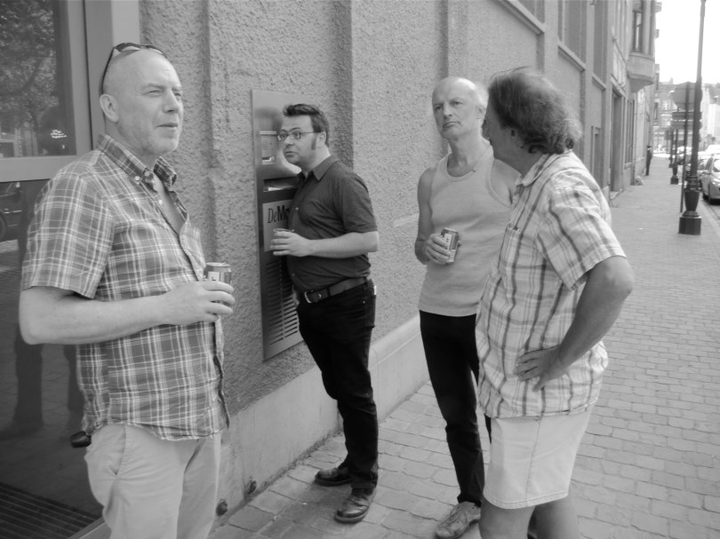 Georges Timmerman (l.) luistert subtiel mee als de organisatoren van het lezersprotest na afloop om een reactie van hoofdredacteur Bart Van Doorne vragen. Als de lijn opeens dood blijkt, kan Timmerman met moeite zijn lach inhouden en denkt hij: als ik een vals gebit had, ik had het nu al ingeslikt.