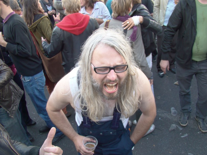 Een eenzame man in tuinbroek schreeuwt zijn levenslust uit over de Vlasmarkt.